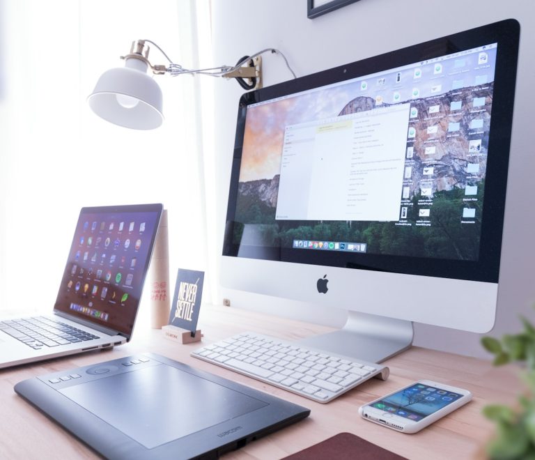 silver iMac near iPhone on brown wooden table